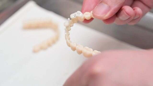 A man use a hand to clean the denture after 3D printer process