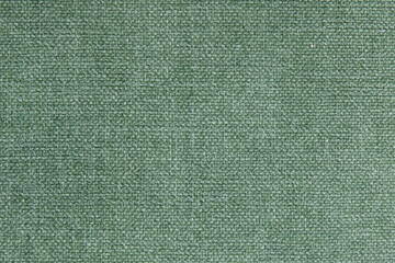 Green textile with tightly woven texture, robust and durable material in an uniform neutral color suitable for various design contexts such as upholstery, carpets and curtains or heavy-duty garments