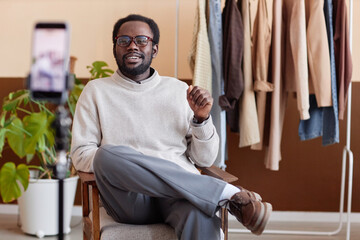 Portrait of adult African American man wearing eyeglasses speaking to smartphone camera while...