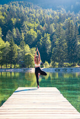 Fototapeta na wymiar Rear view of young female practices yoga in nature