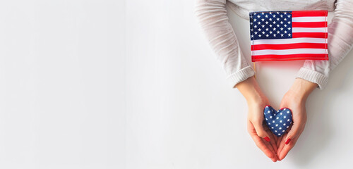 Vibrant American flag held in female hands forming a heart gesture, creating a minimal Memorial Day design with a clean white setting.