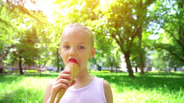 Little kid girl closeup portrait face eating licking ice cream. Happy child eating delicious ice cream outdoor. 