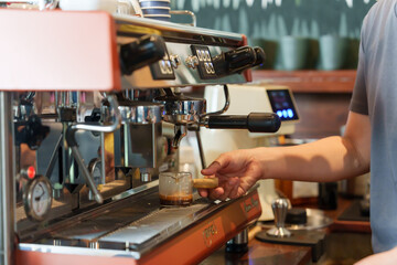 Close-up on hands of barista crafting espresso with professional machine, rich coffee brew flows...
