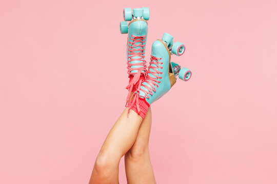 Close up cropped young woman she wearing modern blue rollers rollerblading raise up legs isolated on plain pastel light pink color wall background. Summer season hobby sport lifestyle leisure concept.