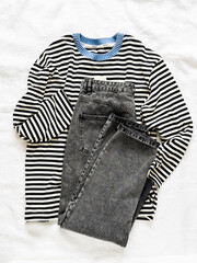 Women's knitted striped longsleeve and gray jeans on a light background, top view