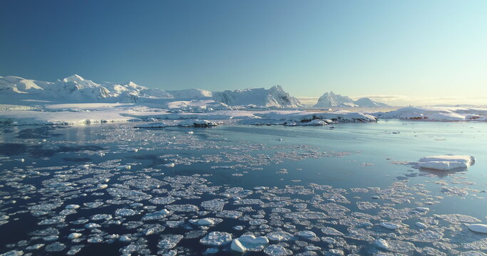 Arctic winter landscape aerial drone . Melting ice on ocean surface. Snow covered mountains, sunny day, sunset. Climate change and global warming. Polar nature environment. Beauty winter scene