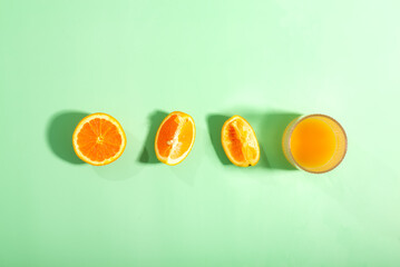 The oranges have been halved and placed on a green surface to emphasize their freshness
