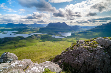 Views of the summits of Suilven, Cul Mor and An Laogh with Loch Sionasgaig and Loch an Doire Dhuibh below from the summit of Stac Pollaidh in the Scottish Highlands on a sunny summers day in the UK