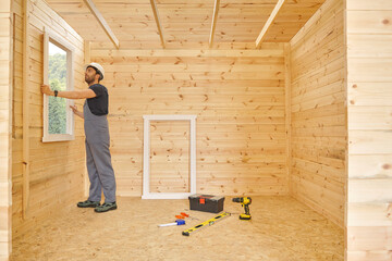 Construction man, builder man construct new wooden home, tiny house style. Spirit level, screw, tool bag and charged drill. Wood shelter style.