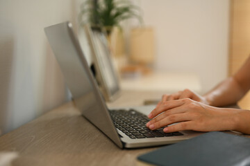 Close up shot of woman hands typing on laptop keyboard working remotely from home