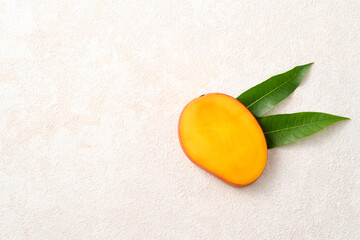 Fresh slice cut juicy mango on gray table background with leaf.