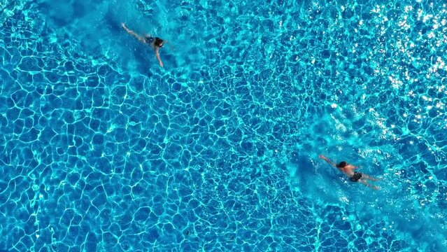 View from above. The couple have fun in the pool. A young attractive couple is relaxing in the pool. Enjoying each other's company.
