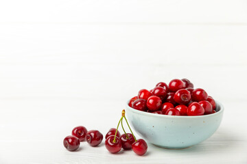 Cherries. Fresh ripe cherries with leaves on a textured wooden background. Fresh sweet organic cherry pile. Berries and fruits. Vegan. Healthy eating. Place for text. Copy space