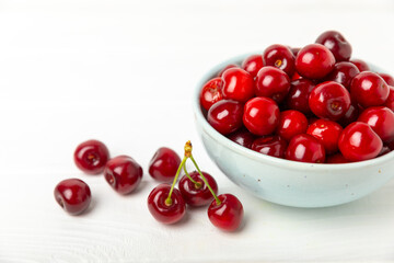 Cherries. Fresh ripe cherries with leaves on a textured wooden background. Fresh sweet organic cherry pile. Berries and fruits. Vegan. Healthy eating. Place for text. Copy space
