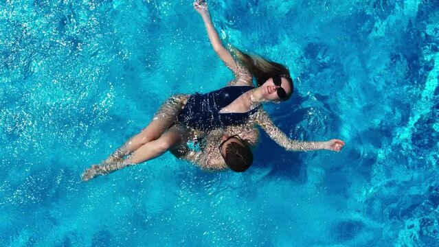 View from above. The couple have fun in the pool. A young attractive couple is relaxing in the pool. Enjoying each other's company.