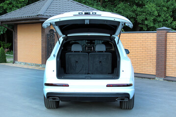 Lux SUV with open empty trunk outdoors. White SUV is ready to load luggage. Clean trunk wagon car....