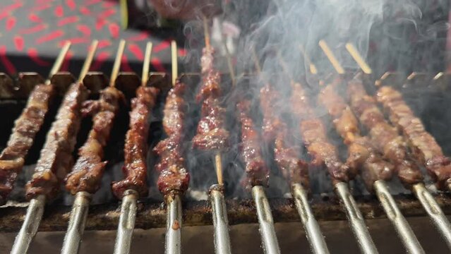 cooking traditional Italian dish arrosticini meat kebabs of lamb on charcoal on the grill