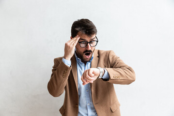 Young successful man in business formalwear looking his wrist watch with late facial expression in...