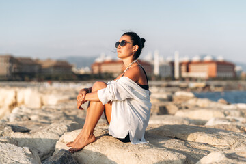 Woman sitting on rock by water