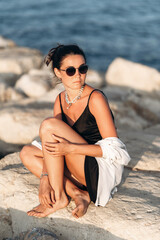 Woman sitting on rock by water