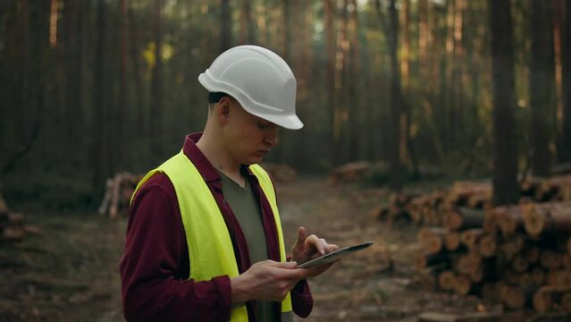 A forest resource engineer conducts a tree cutting audit, holding a tablet in his hands, checking the information and timing of the timber cutting work plan. Sustainable use of natural resources