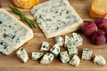 Organic Blue Cheese with Grapes on a Wooden Board, side view.