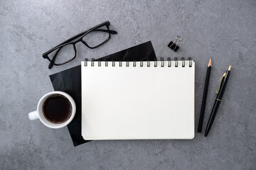 Notebook and coffee on stone texture background. Work desk space