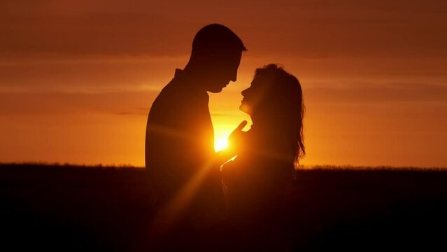 Silhouette of a couple in love in glamor romance at sunset. Love story concept.