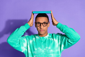 Photo of confidet positive guy dressed turquoise sweatshirt spectacles holding head book isolated...