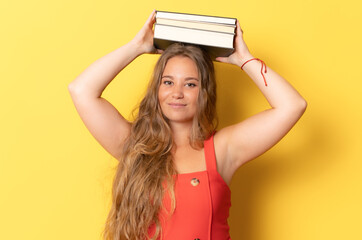 Portrait of smiling woman holding book pile isolated on yellow background.