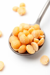 Dry, yellow peas in iron spoon on white background. Close-up
