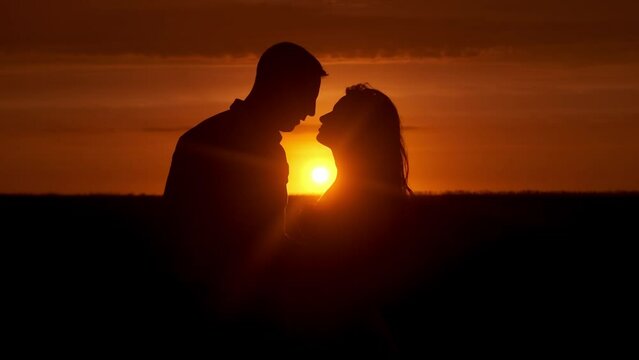 Silhouette of a couple in love in glamor romance at sunset. Love story concept.