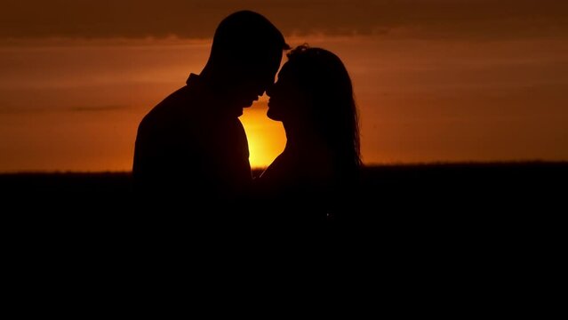 Silhouette of a couple in love in glamor romance at sunset. Love story concept.