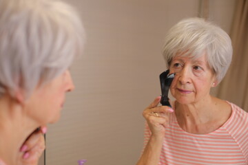 Mature lady using a tool to control her facial hair 