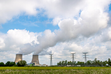 Vue distante d'une centrale nucléaire en fonctionnement émettant des nuages ​​de vapeur....
