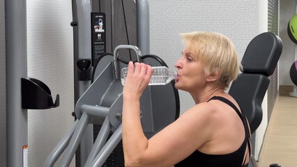 A woman uses a fitness machine and is focused on her workout. The modern interior of the fitness...