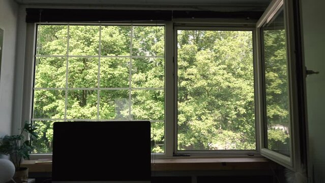 Guy closing the window and blinds of his home office.