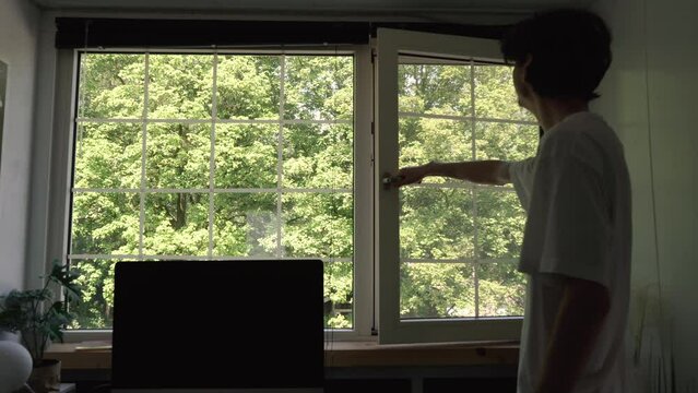 Guy opening his office window letting more airflow to happen.