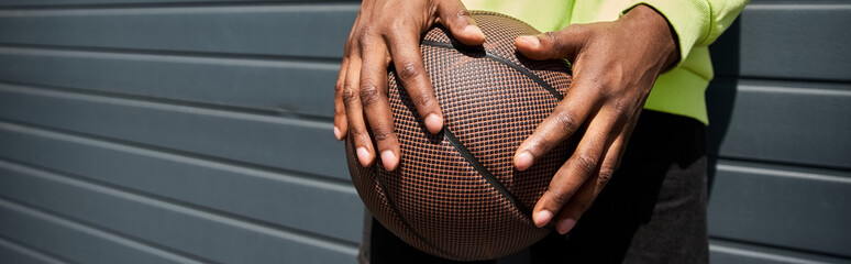 African American man in fashionable attire holding a basketball.