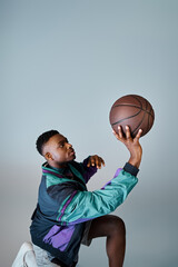 A stylish African American man catches a basketball with skill and precision.