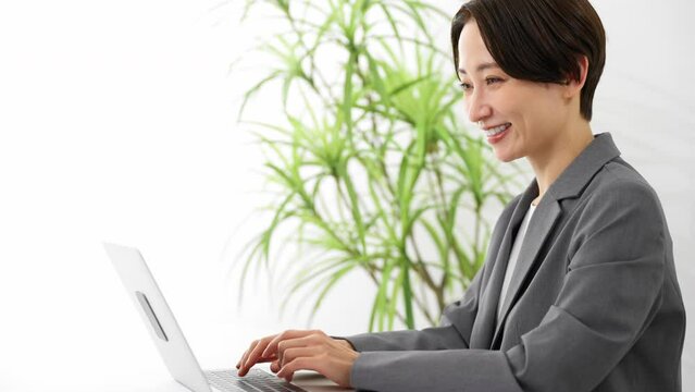 ビジネススーツを着てラップトップを操作している若い女性　ビジネスイメージ
