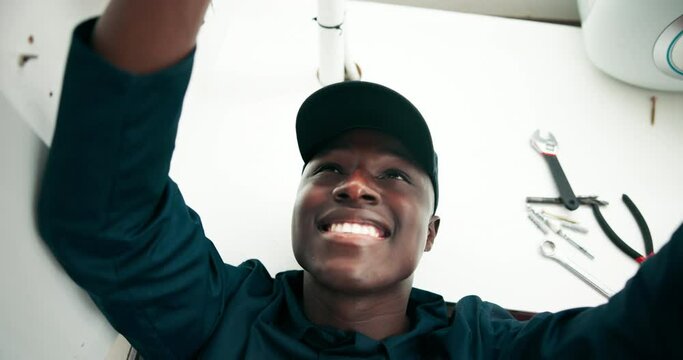 Black man, plumber and pipe with repair for maintenance, leak or fix on sink or service at home. Young African, male person or plumber working on faucet, basin or water leakage in kitchen at house