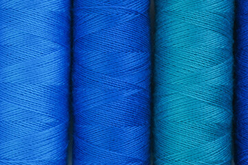 Blue and green spools of thread lined up in a row