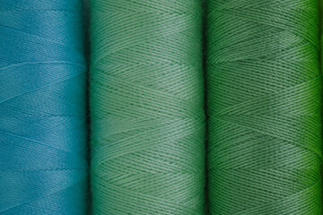 Various colored spools of thread lined up in a row, showcasing a spectrum of colors and sizes