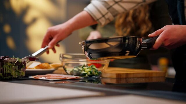 close-up of a house in the kitchen guy prepares dinner with a girl puts croutons on a plate