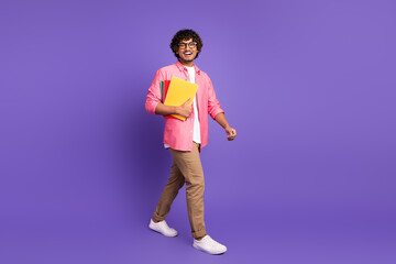Full size photo of nice young man walk book wear shirt isolated on violet color background