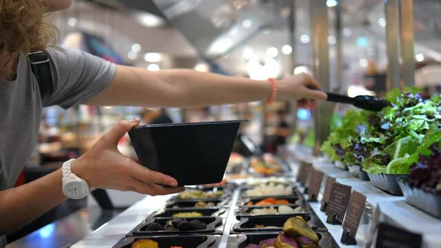 Vegetarian woman is preparing dinner at healthy food point For salad chooses variety of fresh greens as basis of vegetarian diet Vegetarians pay special attention to choice of foods for balanced diet