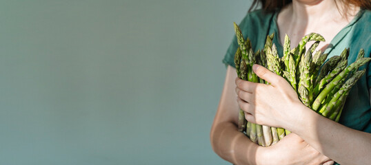 Obraz premium Asparagus. Vegan girl holding fresh asparagus. Juicy healthy farm asparagus, eco agriculture vegetables concept.