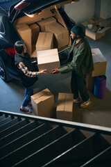 Young couple standing in storage service, holding cardboard box in their hands