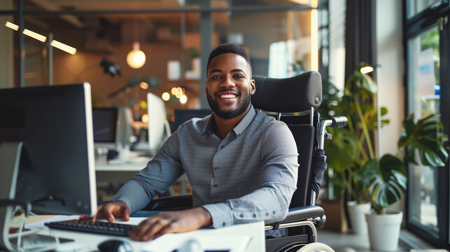 Happy smiling disabled employee man sitting in a wheelchair working in modern office